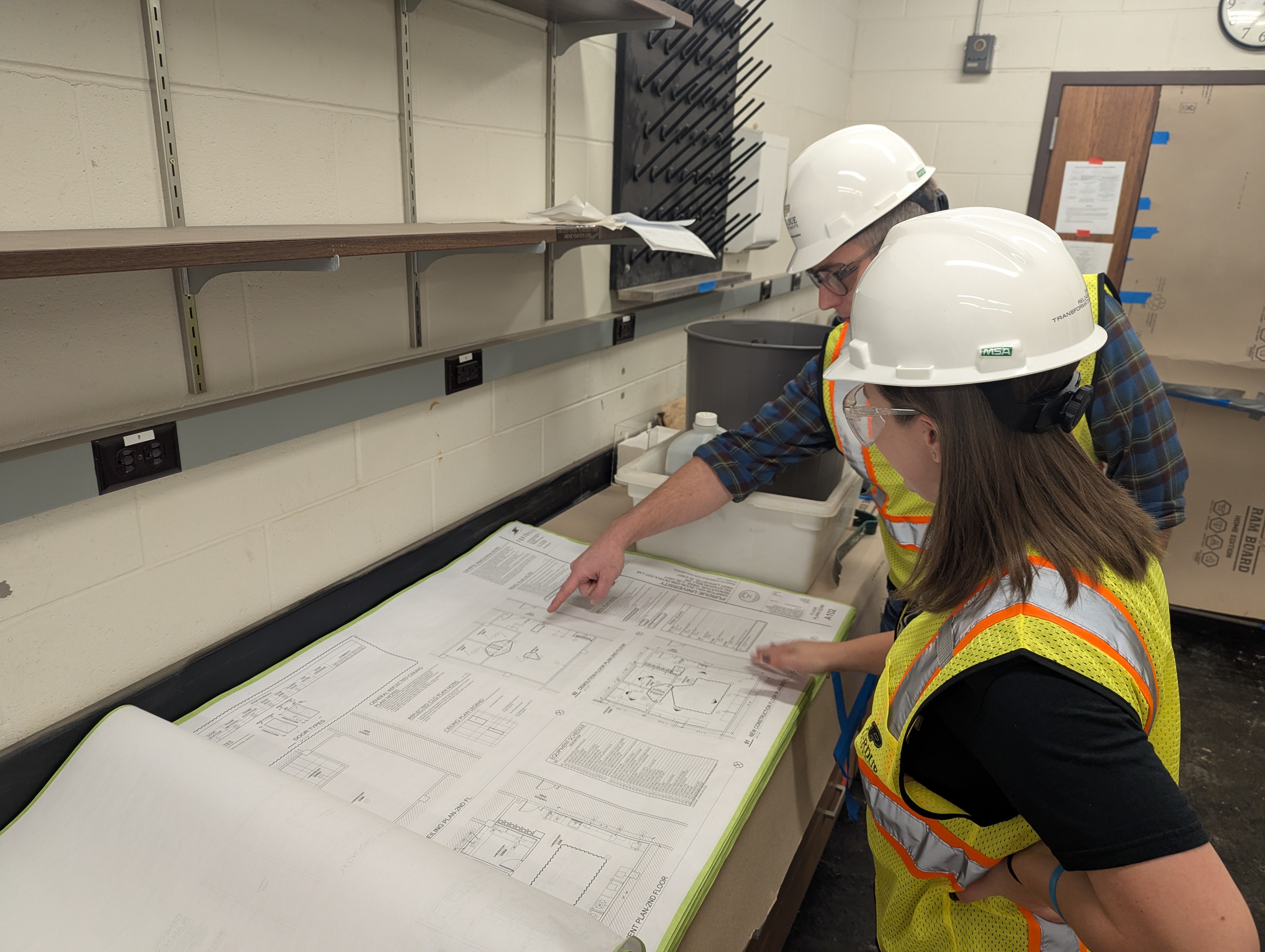 Two people overlooking construction plans