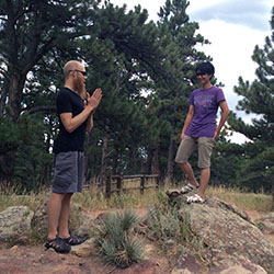 Two students standing in a forested area